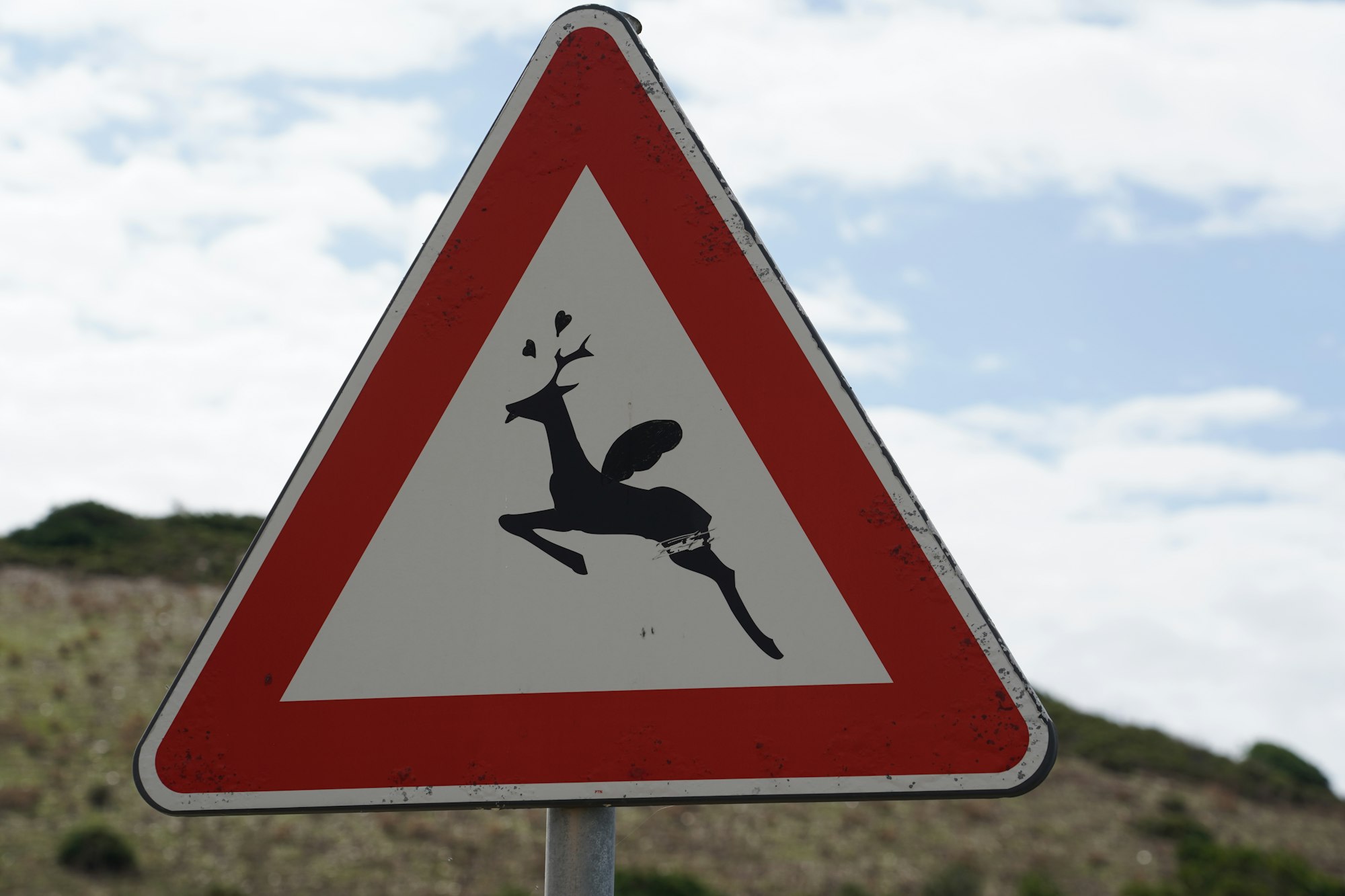 road sign showing deer with wings